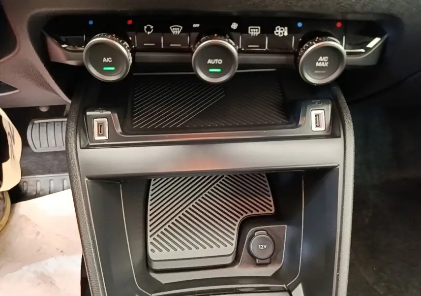 Vue rapprochée de la console centrale noire de la Citroën C4 X 2023 avec commandes climatisation et prises USB et 12V.