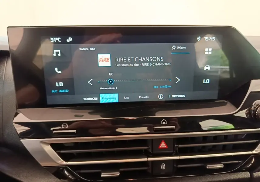 Écran tactile central de la Citroën C4 X noir, affichant la radio et commandes climatisation, vue intérieure frontale.
