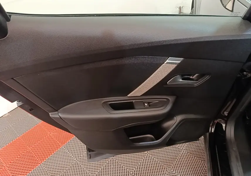 Porte intérieure côté gauche de la Citroën C4 X noire, avec poignée, commande de vitre et insert décoratif gris.