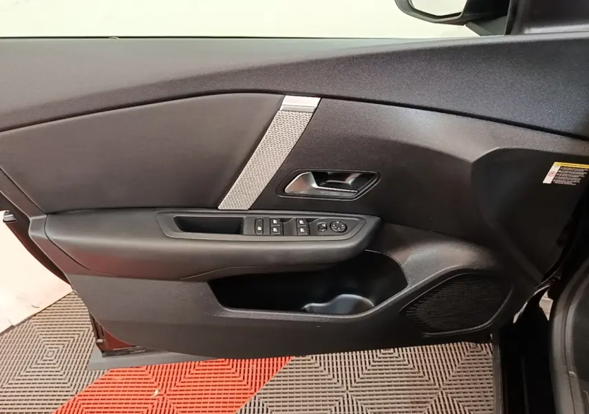Vue intérieure de la porte avant gauche noire de la Citroën C4 X avec commandes de vitres et haut-parleur intégré.
