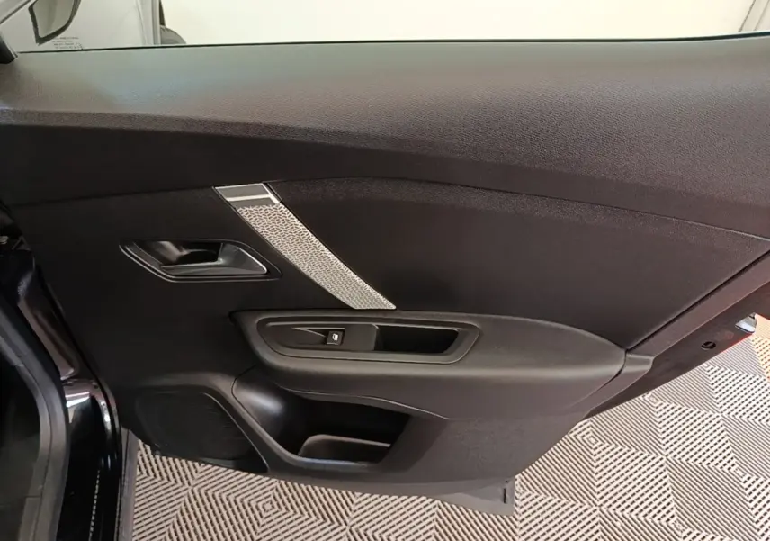 Porte intérieure côté gauche noire de Citroën C4 X 2023 avec poignée et bouton de lève-vitre visible.