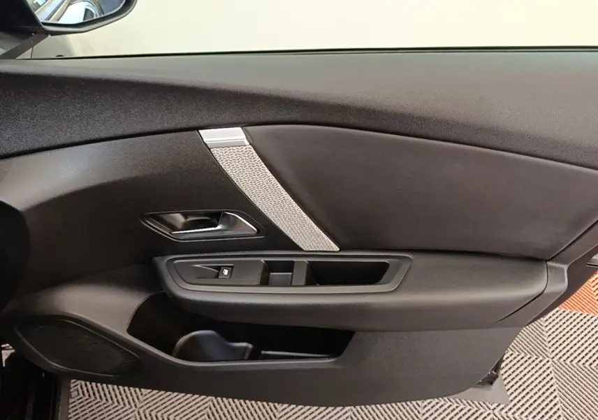 Vue intérieure côté gauche de la porte noire du Citroën C4 X 2023 avec poignée argentée et commande de vitre.
