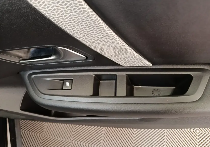 Gros plan sur la poignée intérieure et les commandes de la porte côté gauche d’une Citroën C4 X noire.