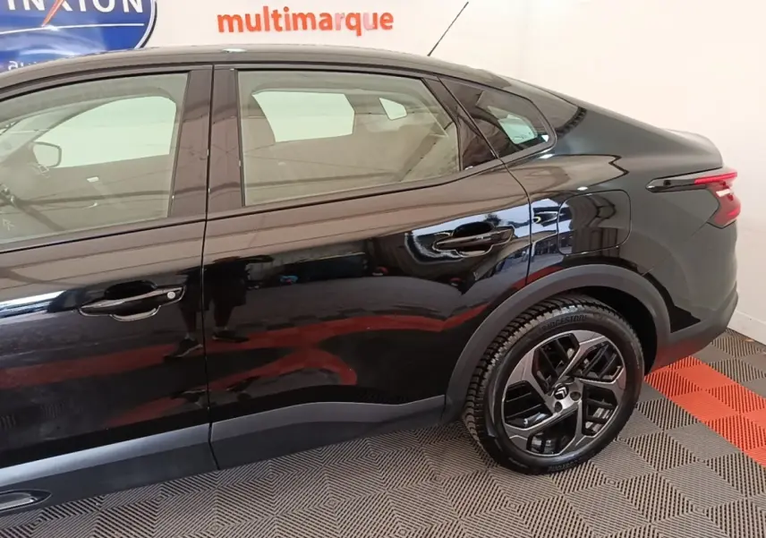 Vue latérale droite de la Citroën C4 X noire 2023, mettant en valeur les jantes et la ligne fluide du toit.