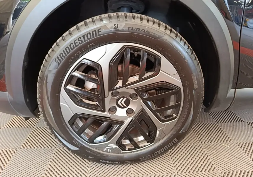Gros plan sur la roue avant gauche noire d'une Citroën C4 X 2023 avec jante au design moderne bicolore.
