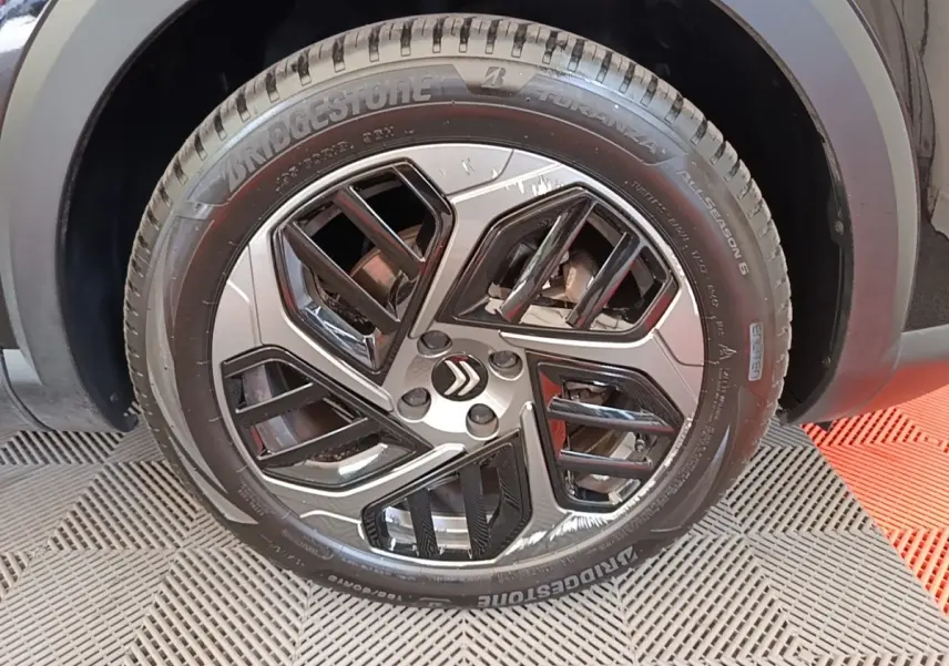 Gros plan sur la roue avant droite noire de la Citroën C4 X avec jante alliage au design moderne.