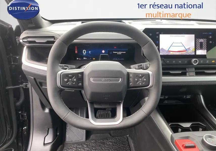 Vue frontale du poste de conduite du Jeep Compass noir Vulcano, avec volant multifonction et écran tactile affichant la caméra de recul.