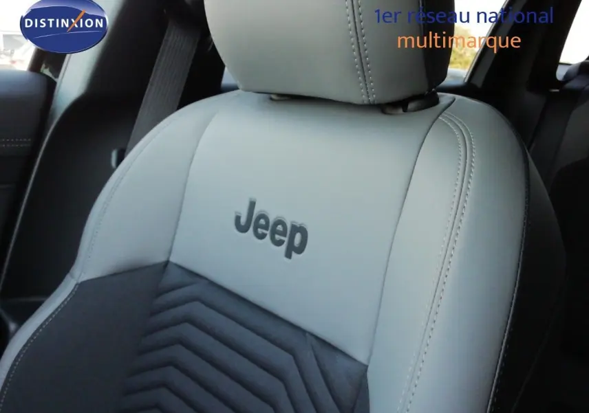 Gros plan sur le siège avant en cuir gris clair et tissu noir du Jeep Compass 2026, logo Jeep brodé au centre.
