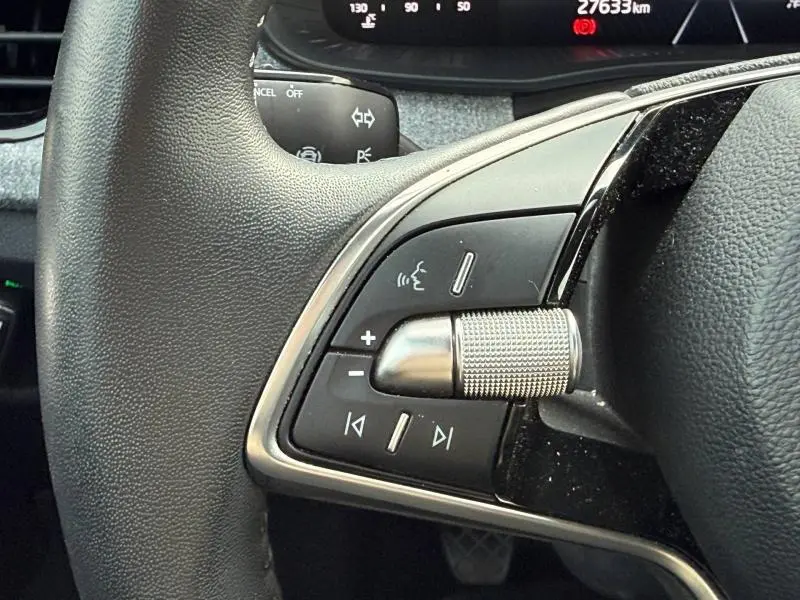Gros plan sur les commandes du volant du Skoda Kamiq 2024, finition noire avec molette métallique texturée.