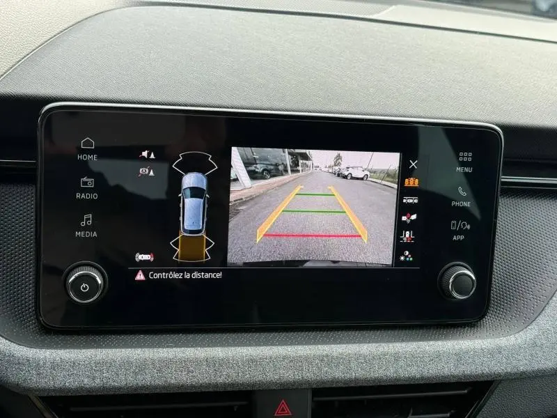 Écran central du Skoda Kamiq 2024 montrant la caméra de recul avec guidage coloré et alertes de distance.