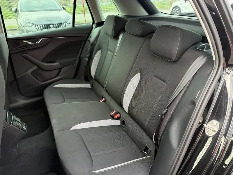 Vue intérieure de la banquette arrière du Skoda Kamiq 2024 noir Magic nacré, avec sièges tissu bicolores et ceinture de sécurité.