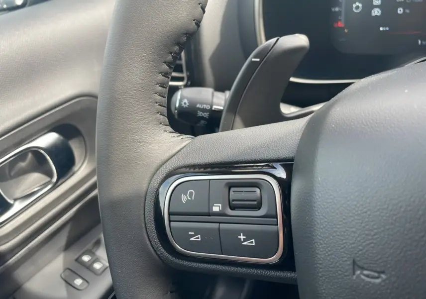 Gros plan sur les commandes du volant côté gauche du Citroën C5 Aircross Hybrid blanc avec toit noir, modèle 2025.
