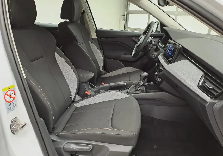 Vue intérieure côté conducteur du Skoda Kamiq blanc Lune 2025, mettant en valeur les sièges bi-matière et la console centrale.