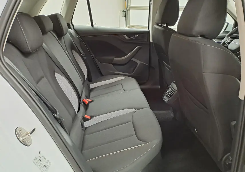 Vue intérieure côté droit des sièges arrière noirs et gris du Skoda Kamiq blanc Lune 2025 avec porte ouverte.