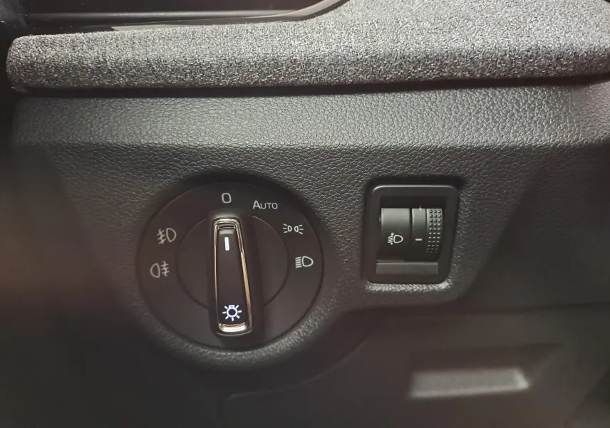 Gros plan sur le bouton de commande des phares dans l’habitacle du Skoda Kamiq blanc Lune 2025.