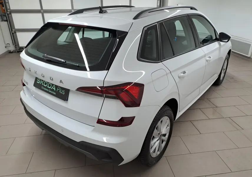 Vue 3/4 arrière droite du Skoda Kamiq blanc Lune 2025, avec barres de toit noires et feux arrière LED distinctifs.
