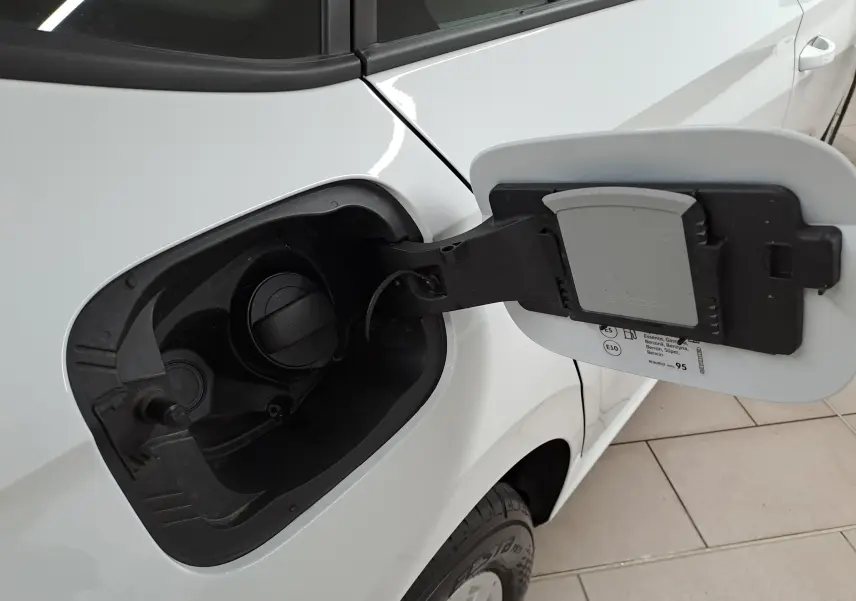 Gros plan sur la trappe à carburant côté gauche d’un Skoda Kamiq blanc Lune, essence, avec bouchon ouvert.
