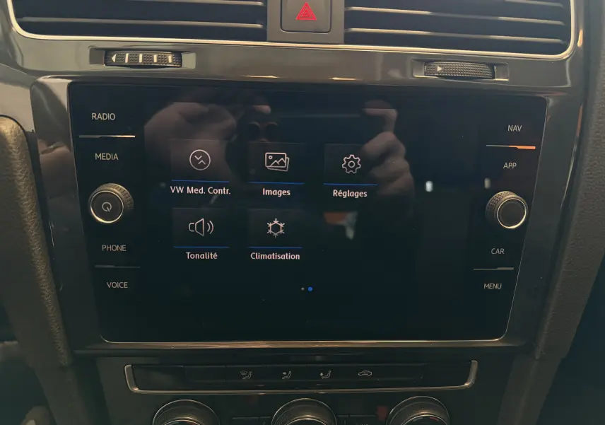 Vue rapprochée de l’écran tactile central noir de la Volkswagen Golf TSI 130 Confortline 2019 avec commandes multimédia et climatisation.