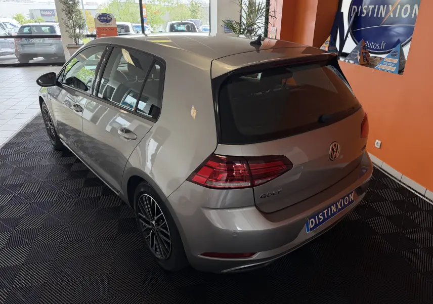 Volkswagen Golf TSI 130 Confortline gris vue 3/4 arrière droit en intérieur avec jantes alliage et vitres teintées.