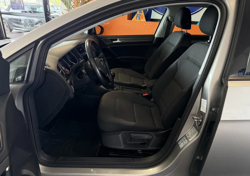 Vue intérieure côté conducteur d'une Volkswagen Golf TSI 130 Confortline gris, montrant sièges et tableau de bord.