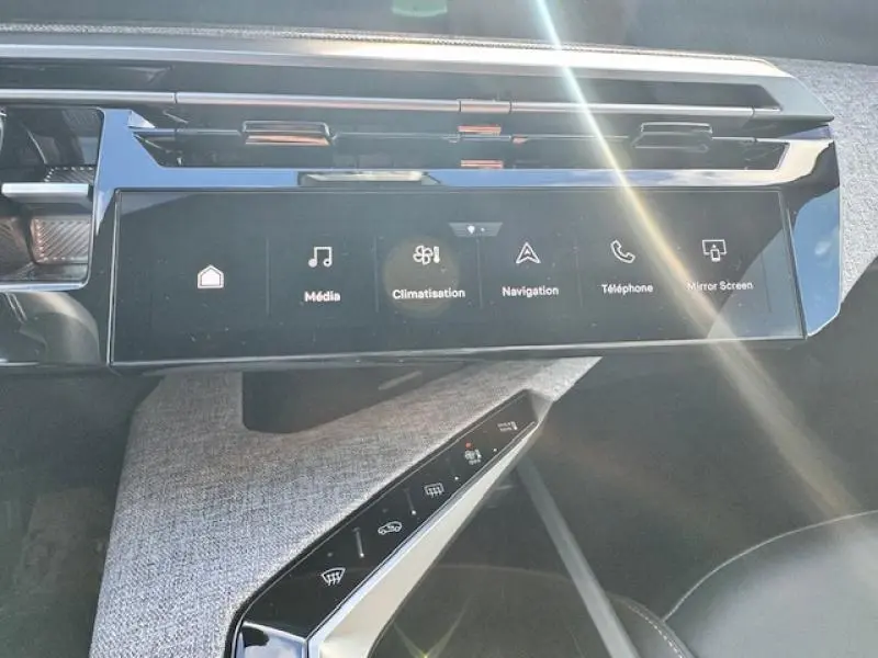 Vue rapprochée de la console centrale noire brillante du Peugeot 5008 Hybrid avec écran tactile et commandes climatisation.
