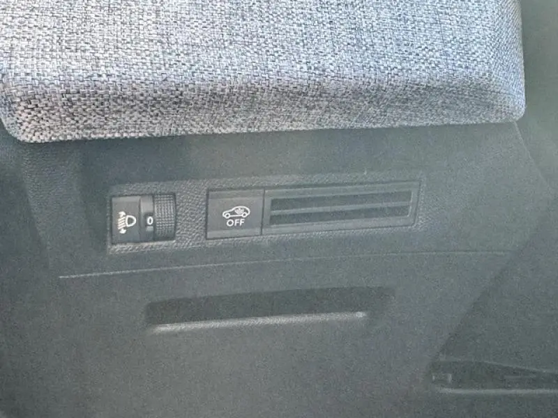 Détail intérieur montrant les commandes de réglage des phares et de désactivation de l'assistance au maintien sur PEUGEOT 5008 noir.