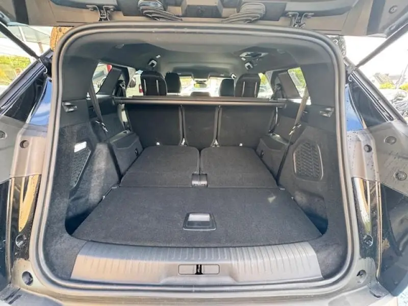 Coffre ouvert en vue arrière du Peugeot 5008 noir Perla Nera avec banquette arrière rabattue pour un grand espace de chargement.