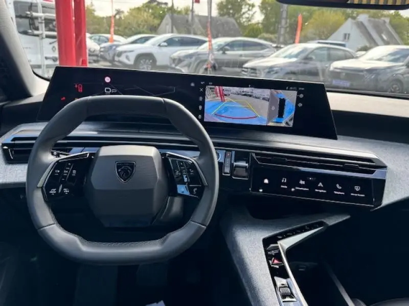 Vue intérieure du tableau de bord du Peugeot 5008 Hybrid noir, avec volant multifonction et écran tactile affichant la caméra de recul.