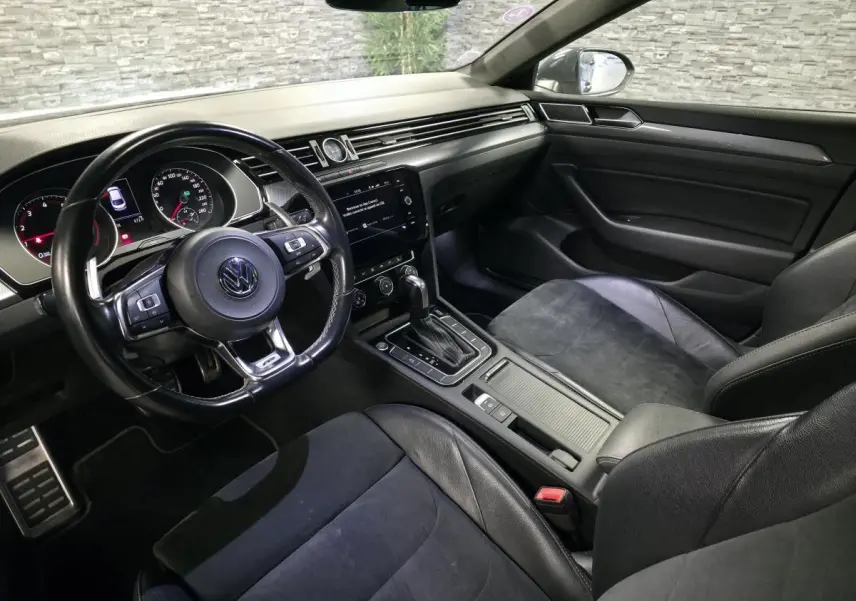 Vue intérieure côté conducteur du Volkswagen Arteon 2.0 TSI gris, avec volant cuir R-Line et console centrale moderne.