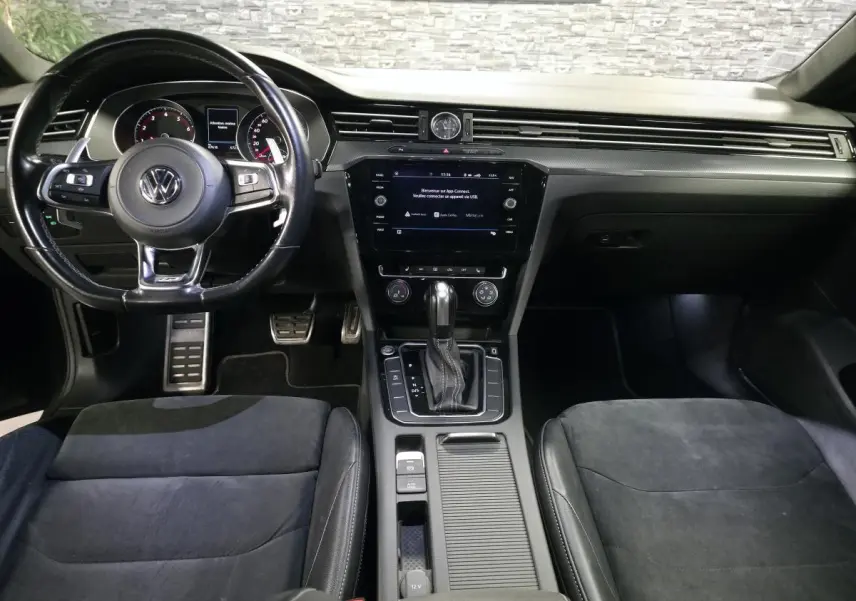 Vue intérieure frontale du Volkswagen Arteon 2020, tableau de bord noir avec volant cuir multifonction R-Line et console centrale.