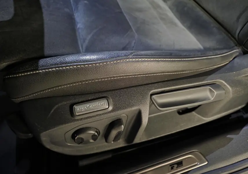 Gros plan sur le réglage électrique du siège avant gauche en cuir noir avec badge ergoComfort et seuil de porte R-Line.