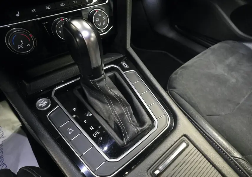Gros plan sur la console centrale noire avec levier de vitesse automatique cuir et boutons de commande d’une Volkswagen Arteon gris.