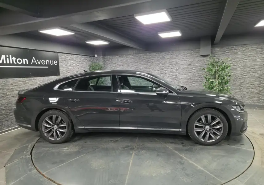 Vue latérale droite d'une Volkswagen Arteon gris foncé R-Line 2020 en intérieur avec jantes alliage 18 pouces.