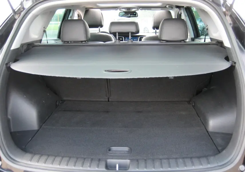 Vue arrière du coffre ouvert du Hyundai Tucson noir Fantom Metal, avec cache-bagages et sièges arrière en cuir visibles.