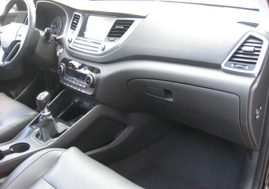 Vue intérieure côté passager du tableau de bord noir du Hyundai Tucson 2016 avec levier de vitesses manuel et sièges cuir.