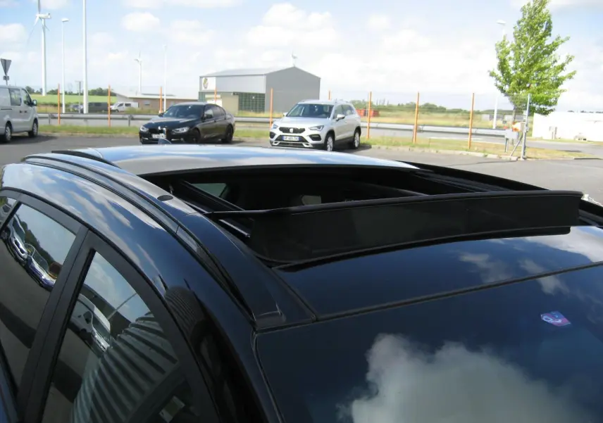 Vue en plongée du toit ouvrant ouvert sur le côté gauche d’un Hyundai Tucson noir fantom metal stationné en extérieur.
