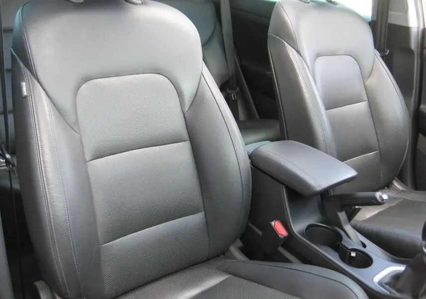 Gros plan sur les sièges avant en cuir noir du Hyundai Tucson 2016, avec accoudoir central et console entre les deux.
