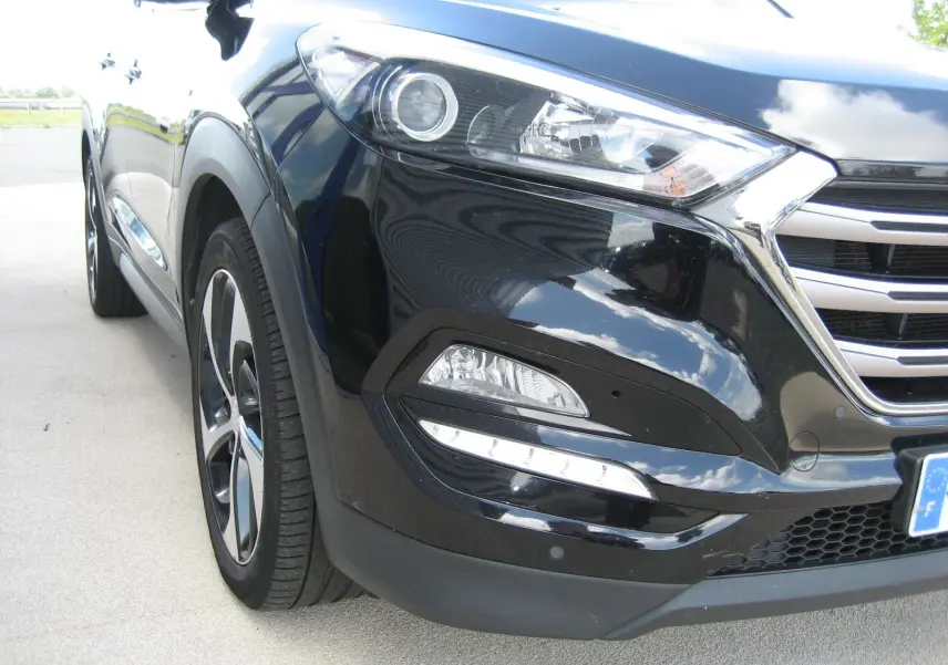 Vue 3/4 avant gauche du Hyundai Tucson noir fantom metal, mettant en valeur les phares LED et la calandre chromée.