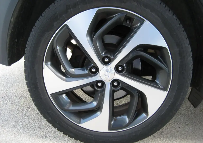 Vue rapprochée sur la roue arrière gauche d'un Hyundai Tucson noir fantom metal, soulignant le pneu et l'aile du véhicule.