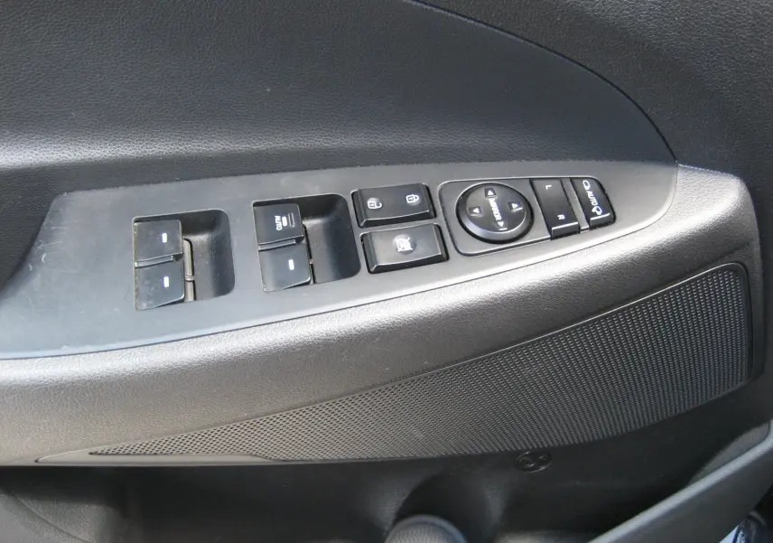 Gros plan sur la commande des vitres et rétroviseurs côté conducteur d’un Hyundai Tucson noir fantom metal de 2016.