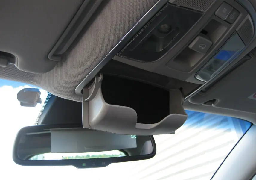 Vue intérieure du rangement lunettes ouvert au plafond d'un Hyundai Tucson noir, avec rétroviseur et commandes de toit visibles.