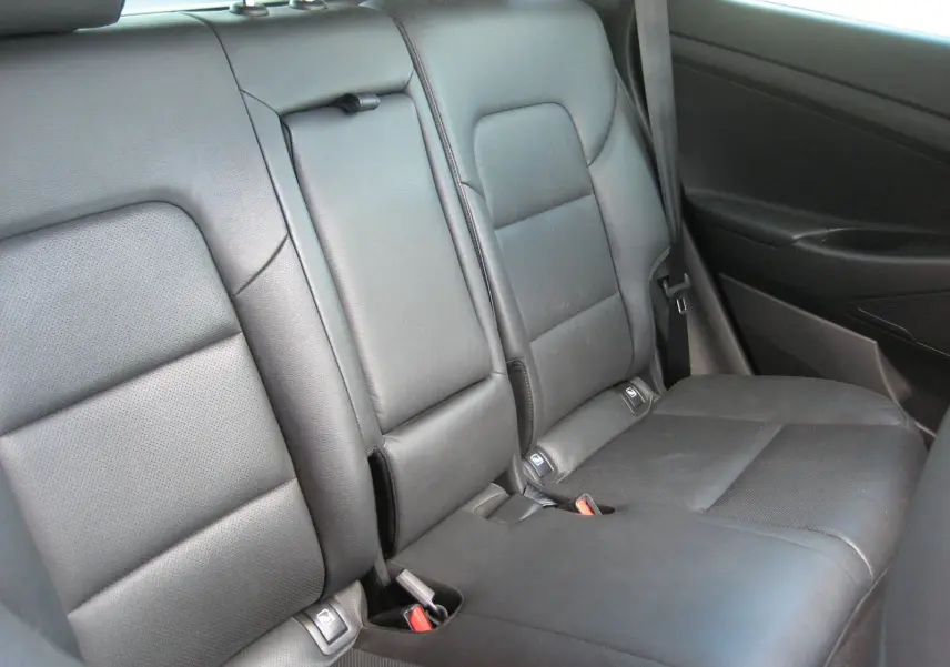 Vue intérieure montrant la banquette arrière en cuir noir avec accoudoir central relevé du Hyundai Tucson 2016.