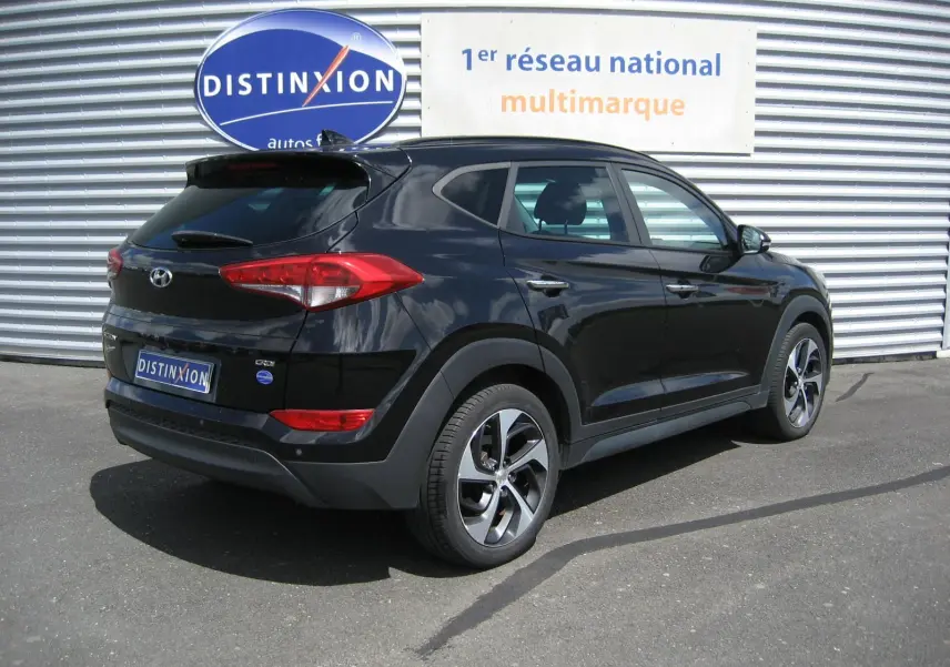 Hyundai Tucson noir fantom metal vu en 3/4 arrière droit, avec jantes alliage et feux arrière distinctifs.