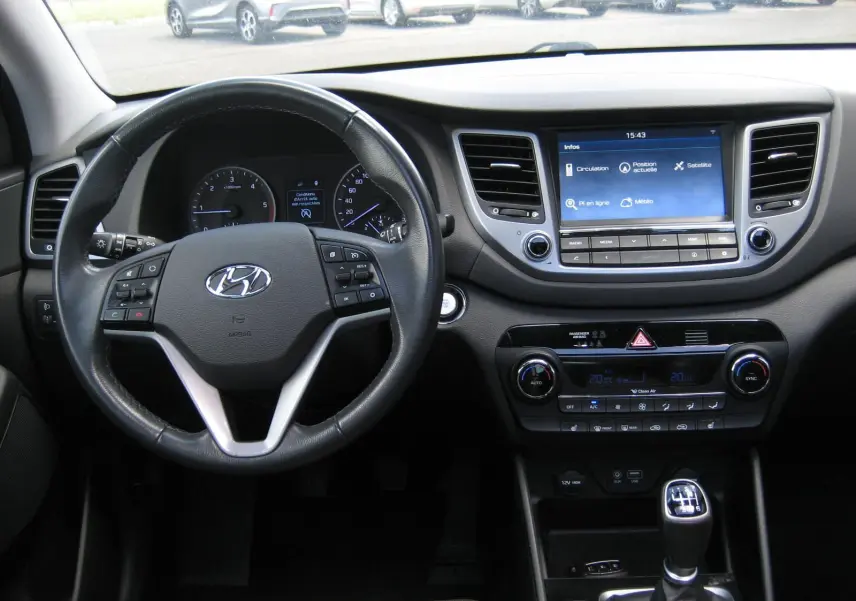 Vue intérieure du tableau de bord du Hyundai Tucson 2016, avec volant cuir noir et écran tactile central allumé.