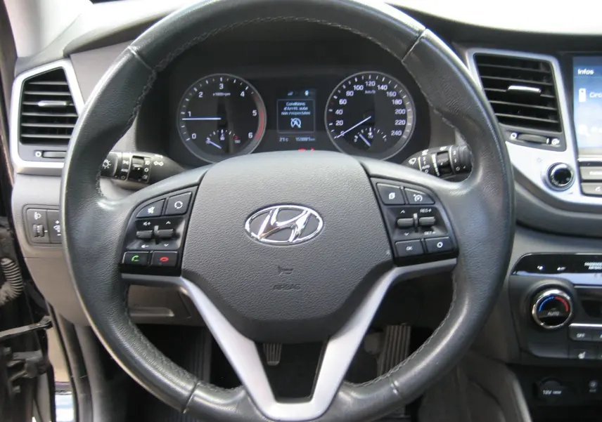 Vue rapprochée du volant en cuir noir du Hyundai Tucson 2016, avec tableau de bord et commandes visibles.