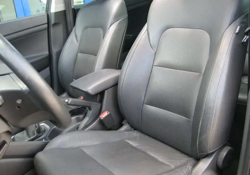 Vue intérieure rapprochée des sièges avant en cuir noir du Hyundai Tucson 2016, avec accoudoir central et volant partiel visible.