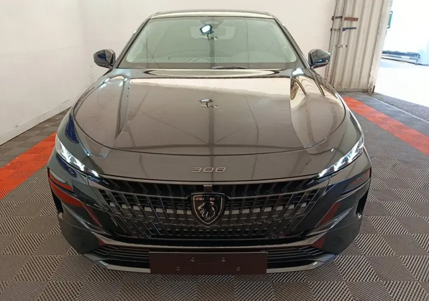 Vue frontale d'une Peugeot 308 noire 2026 avec calandre noire et logo lion central bien visible.