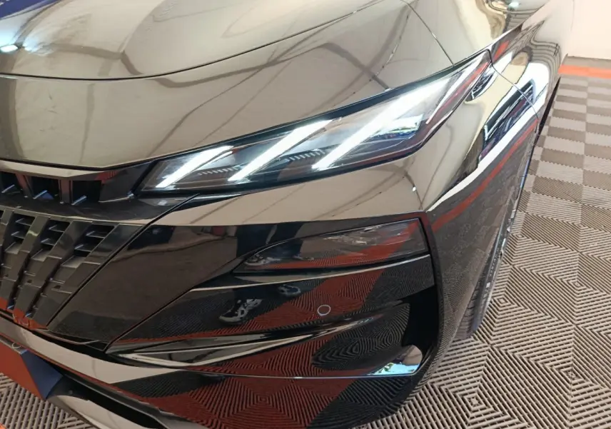Gros plan sur l'avant droit noir brillant de la Peugeot 308 2026 avec phares LED allumés et calandre distinctive.