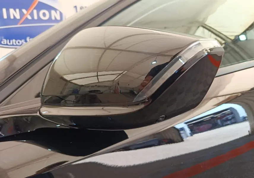 Rétroviseur côté gauche noir brillant de la Peugeot 308 2026, reflet d'un garage intérieur visible.