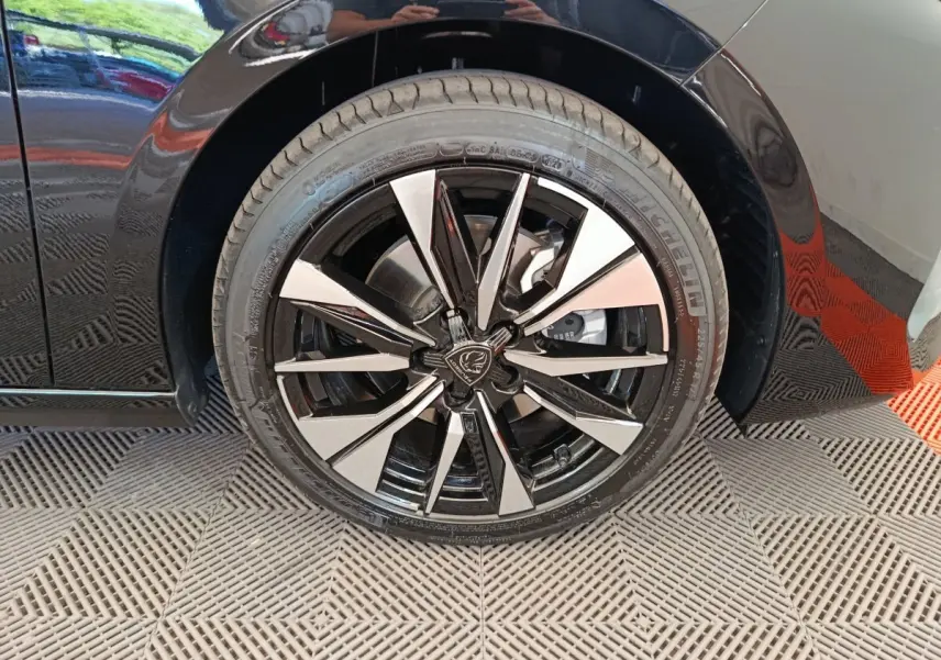 Gros plan sur la roue avant gauche noire d’une Peugeot 308 2026, jante alliage bicolore au design moderne.